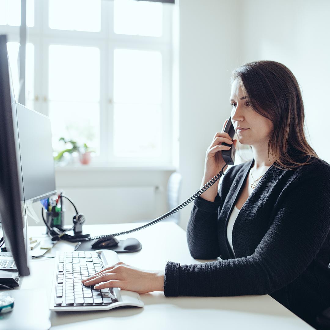 AdvoNeo Mitarbeiterin sitzt vor dem Laptop und berät Mandanten am Telefon