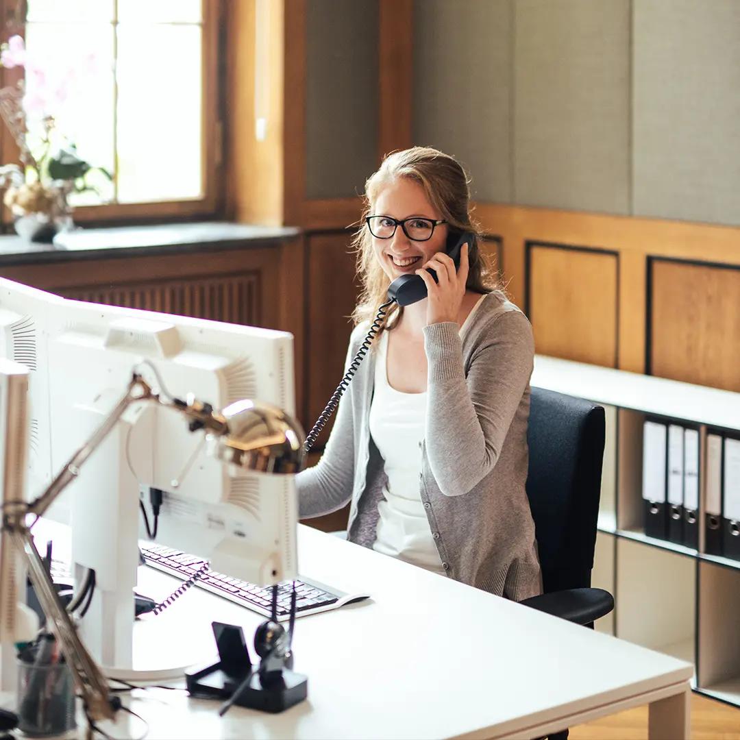 AdvoNeo Mitarbeiterin telefoniert mit Mandanten und lächelt