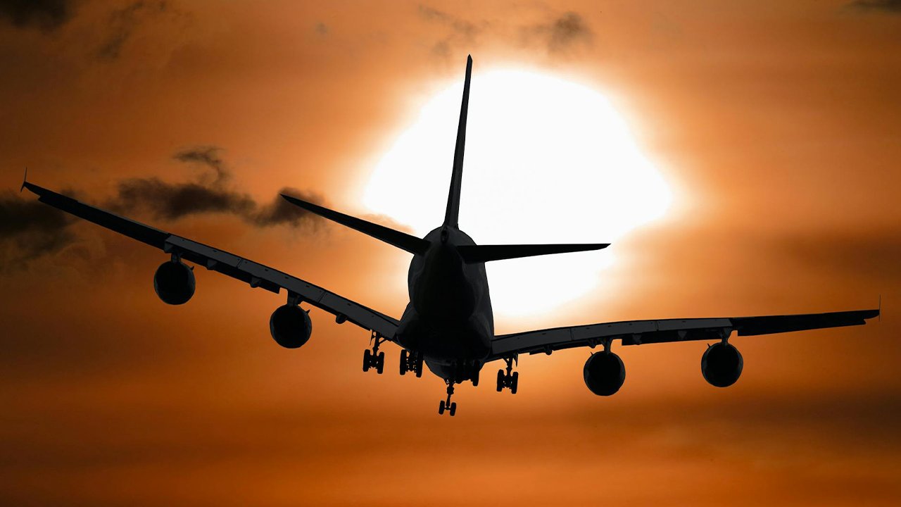 Flugzeug fliegt in den Sonnenuntergang: Der Traum vom Auswandern mit Schulden