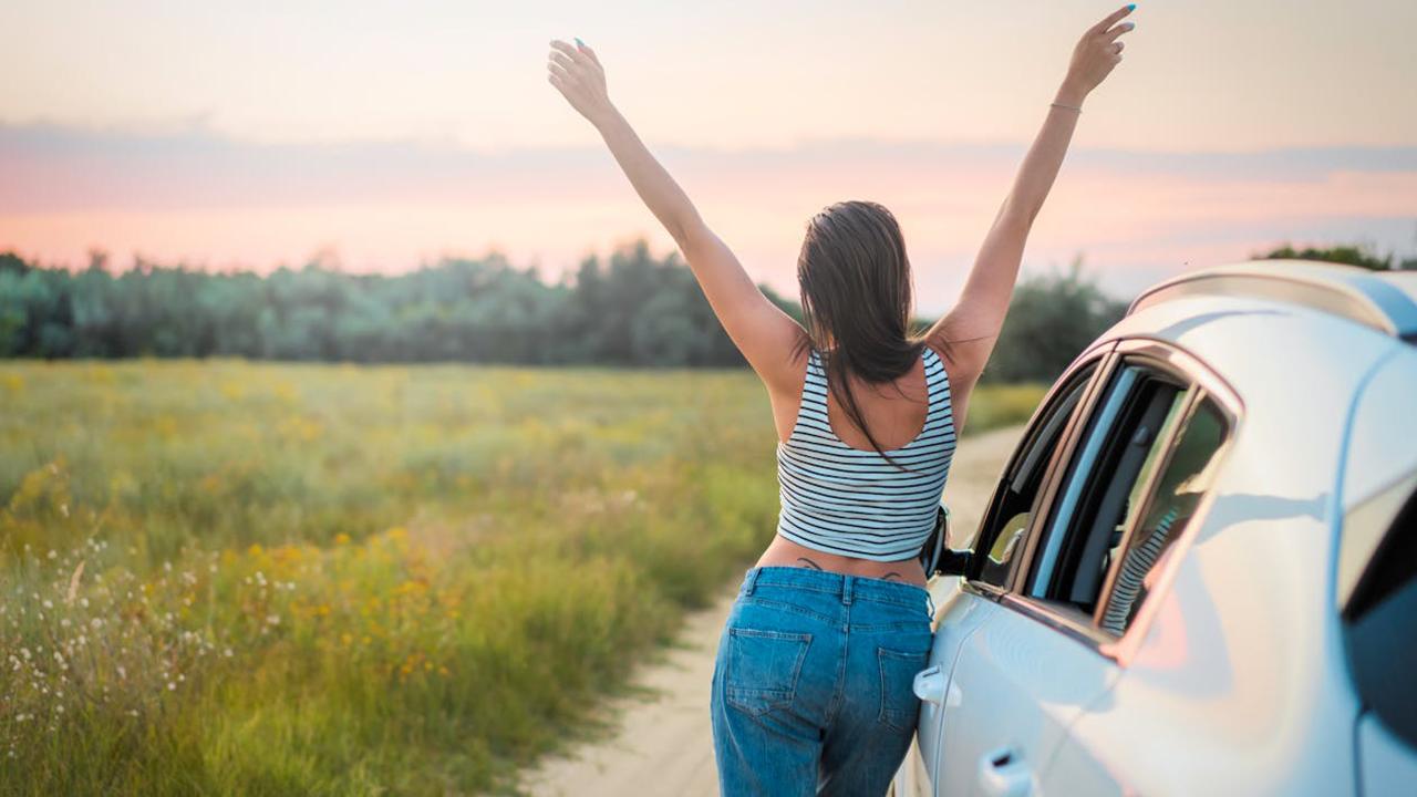 Auto behalten, Pfändung verhindern: glückliche Frau steht neben Auto