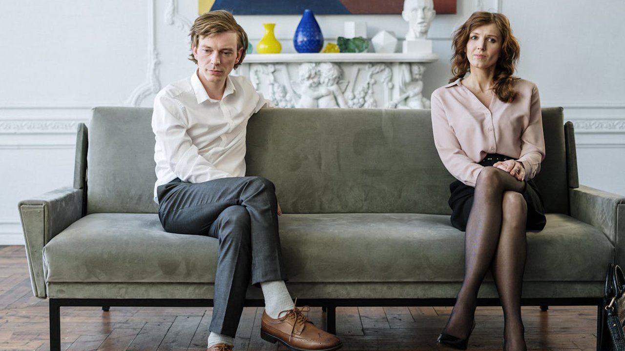 Schulden bei Scheidung und Trauerfall: geschiedenes Ehepaar sitzt auf Sofa