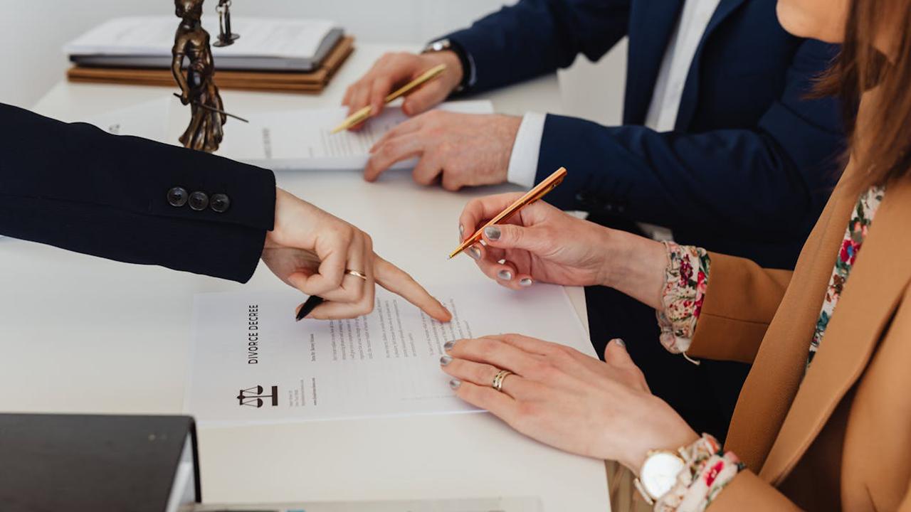 Schulden bei Scheidung Haftung (Symbolbild): Paar unterschreibt Scheidungsdokument