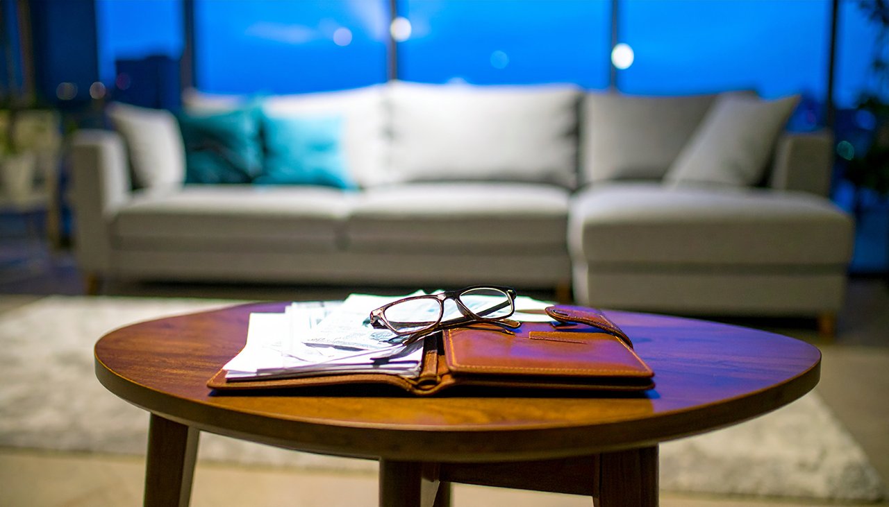 Symbolbild: Finanzielle Belastung trotz gutem Lebensstandard - Dokumente und Notizbuch auf edlem Holztisch