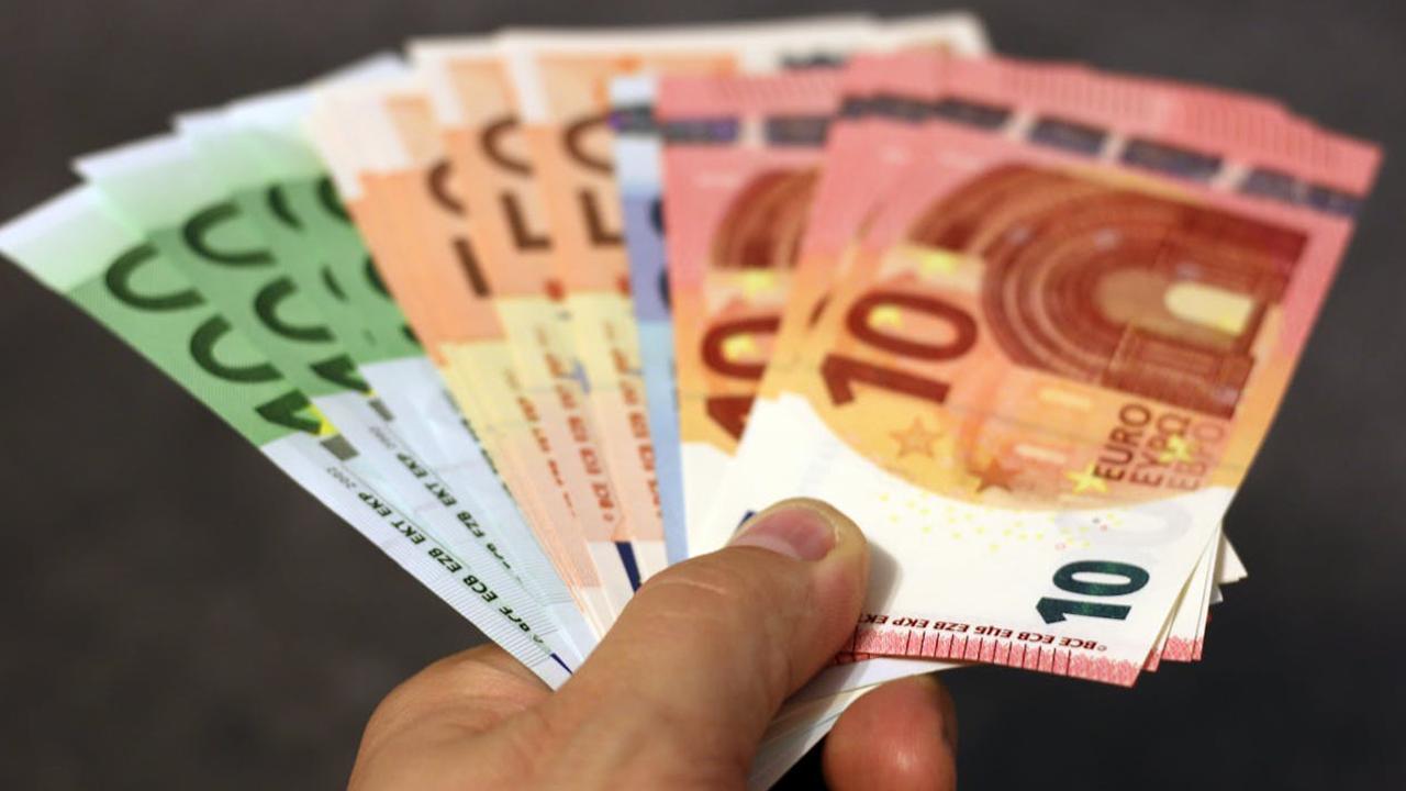 Geld bezahlen Schulden zurückzahlen / Hand mit Geldscheinen