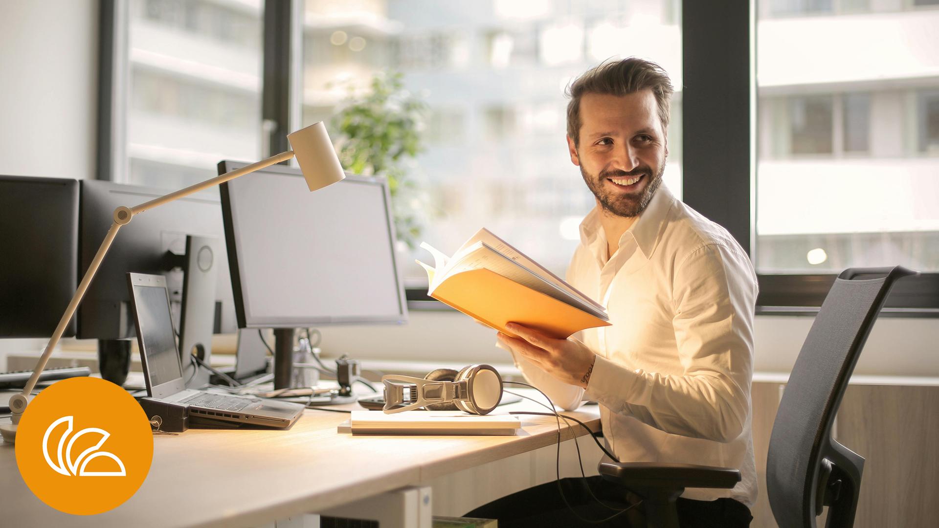 Schuldenfrei Ratgeber Hero AdvoNeo_lächelnder Mann mit Buch und Laptop