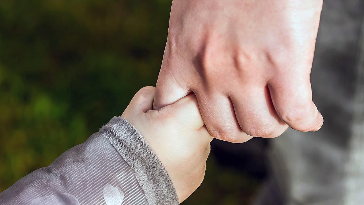Schulden Scheidung Kindesunterhalt (Symbolbild): Kinderhand hält Hand des Elternteils