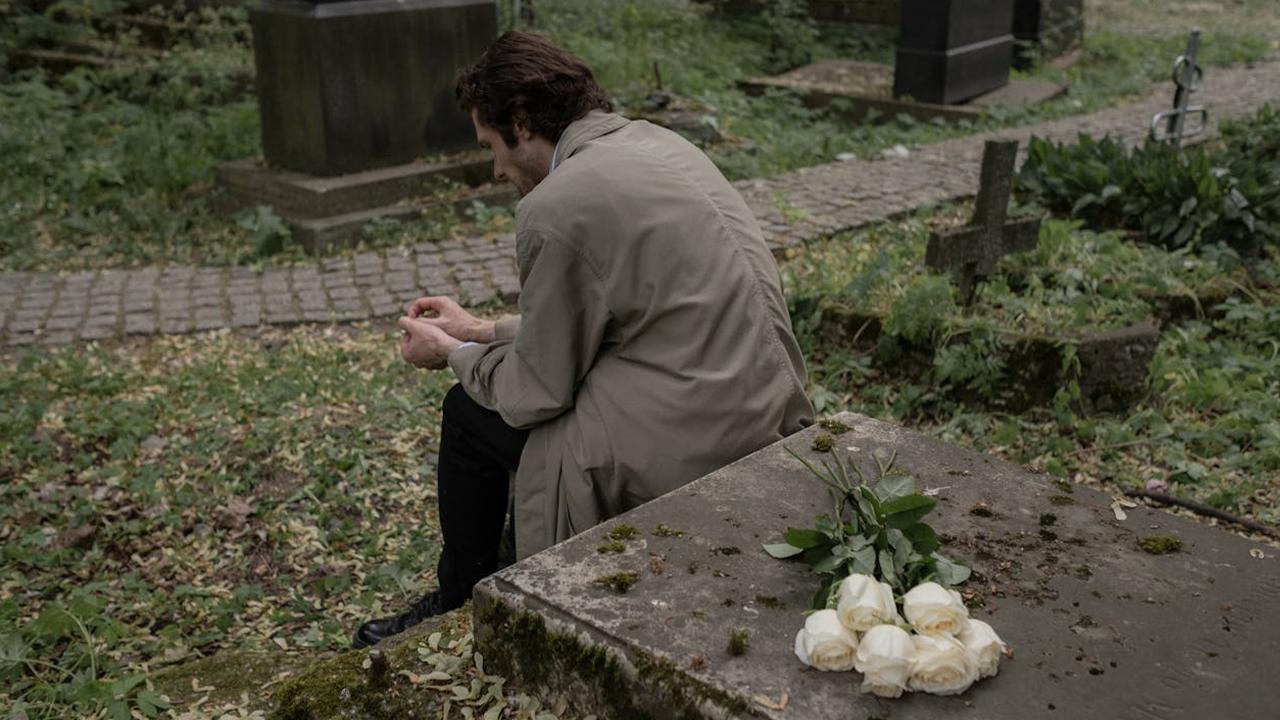 Schulden im Trauerfall erben_Mann besucht Friedhof